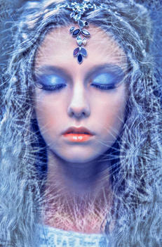 Winter beauty shot of the female model, she is like a snow queen. Her eyes are closed.