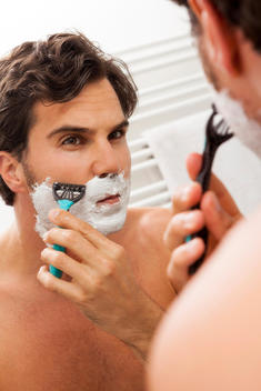 Mirror image of man shaving in the morning