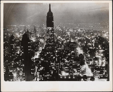 Aerial View At Night Facing South Of The Rca Building In The Foreground Left And The Empire State Buidling. The Lights Of 5Th Ave. (Left) And 6Th Ave. (Right) Are Visible.