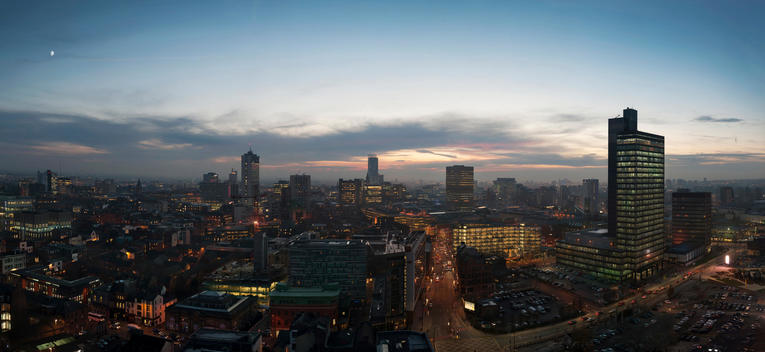 Manchester at dusk as the lights in the buildings of the city come on.