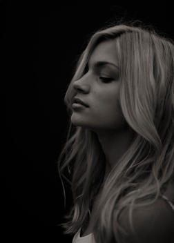 Black and white profile of a beautiful blonde women against a black backdrop.