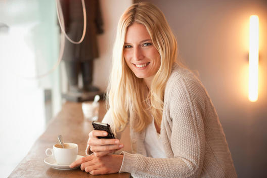 Portrait of young woman holding cellphone in cafe