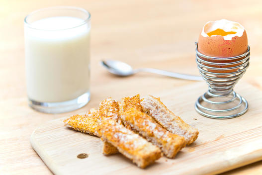 Boiled egg and soldiers with glass of milk
