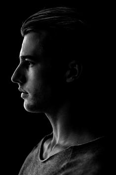 A profile shot of a young man on black