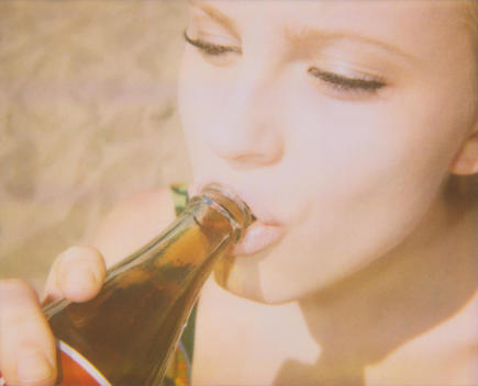 Retro 1970s portrait of an attractive woman sipping from a vintage coke bottle