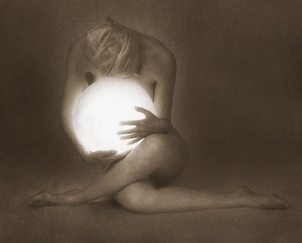 Anonymous nude woman gracefully seated with legs crossed, holding luminous lit globe in her lap