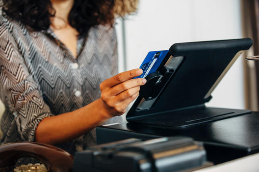 Mixed race clerk swiping credit card at register