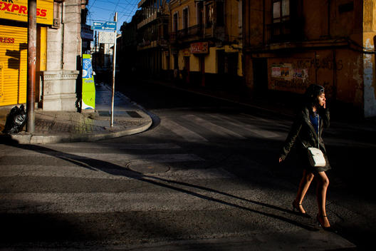 A Young Woman Walks Down Calle Bolivar In Front Of Old Buildings While Talking On Her Cell Phone.