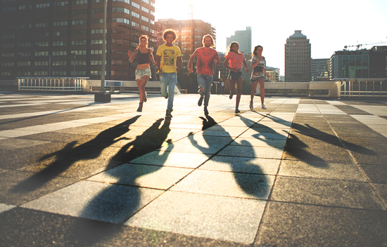 teens running towards camera sunset shadows cool urban clothes