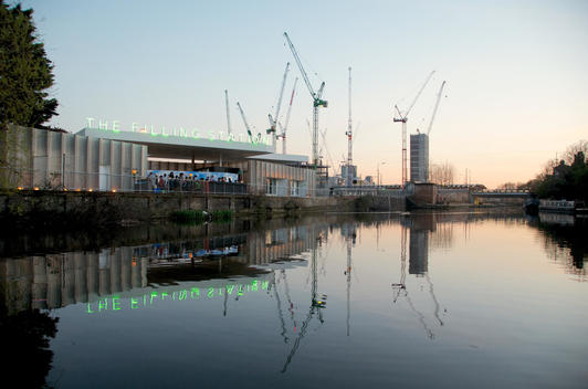 London construction site at King\'s Cross station with high cranes against night sky with restaurant on canal