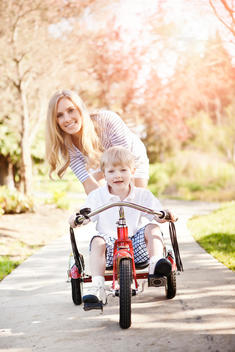 Mother and son (2-3) riding tricycle in park