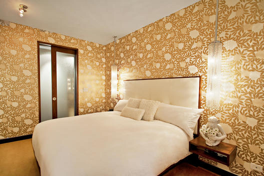 Bedroom With Gold Printed Wallpaper And Frosted Glass Bathroom Doors