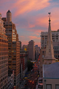 Fifth Avenue, The Flatiron Building, And The Rooster Weathervane On Top Of The Fifth Ave. Church At Sunset