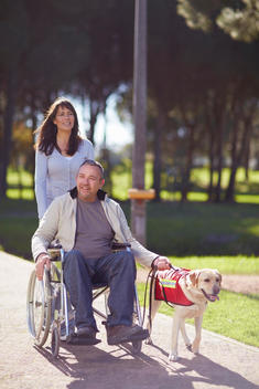Woman with man in wheelchair and dog in park