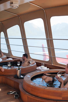 a group of men relaxing in hot tubs with wine aboard the Nomads of the Seas Atmosphere ship