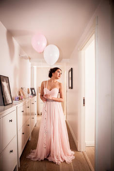 Young woman in evening gown daydreaming in hallway