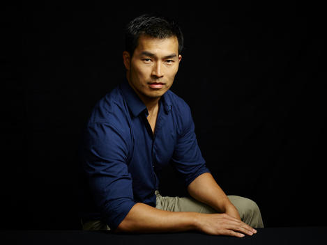 Black background portrait of Asian male 30?s strong jaw.