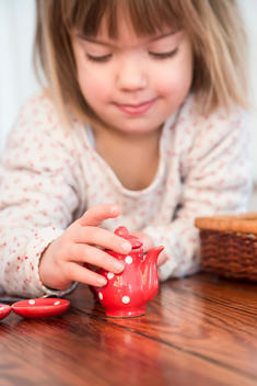 Little girl playing with dolls china set