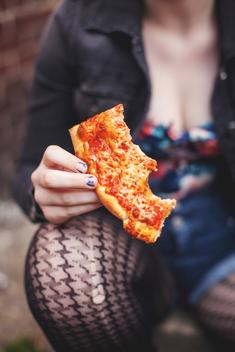 Close up view of young woman\'s hand holding pizza