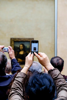 A crowd of tourists takes pictures of the Mona Lisa at the Louvre museum in Paris, France.