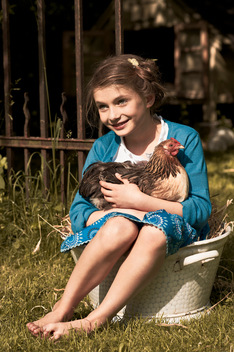 Little girl holding a rooster in its arms