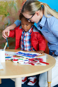 toddler learning how to paint and use a brush with teacher
