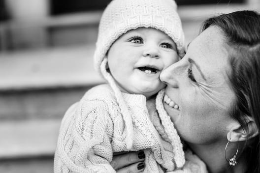 Black and white, Close up image of mom and baby girl in white winter hat, laughing and smiling on city steps