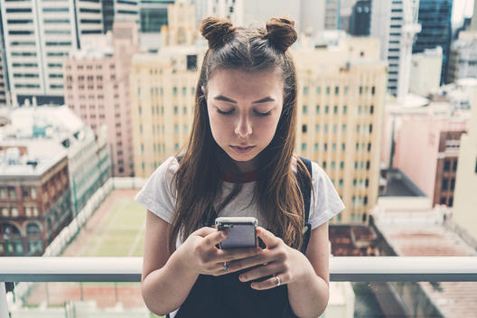 Teenage Girl on Smartphone. City Backdrop