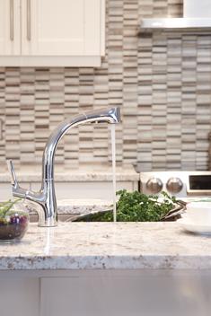 A tap running water in a modern designed kitchen to wash fresh herbs.