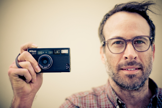 Portrait of actor Jason Lee holding a camera.