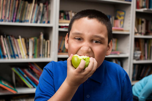 Student eating apple in library