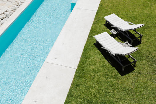 Lounge chairs on grass along lap pool