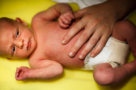 A newborn boy gets a gentle touch after a diaper change.