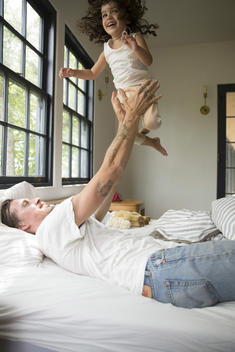 dad in bed holding daughter above him