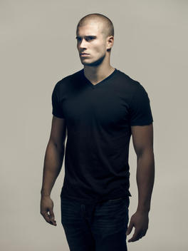 Portrait of a young man with a shaved head wearing a black t-shirt.