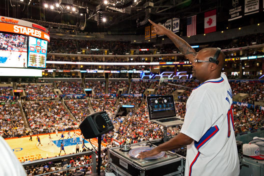 A d.j. points in the air as he works at the Staples Center during a basketball game