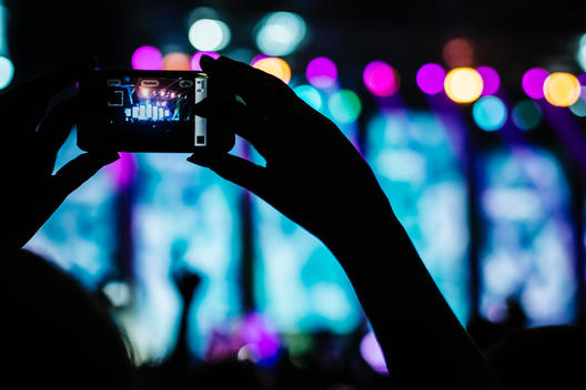 A fan takes a picture at a rock concert with their phone.