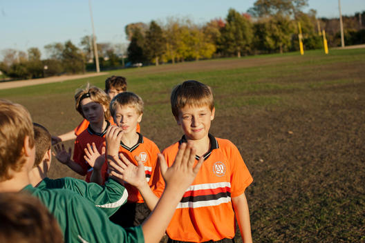 Two Soccer Teams Give High Fives After A Game In A Chicago Park.