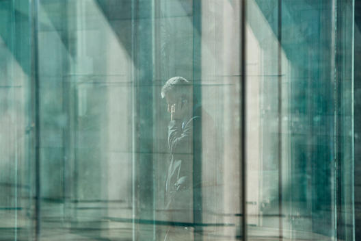 Businessman Behind Panes Of Glass Speaking On Phone