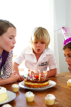 kids blowing birthday cake candles
