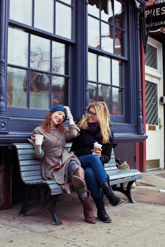 friends socializing on a bench while drinking coffee