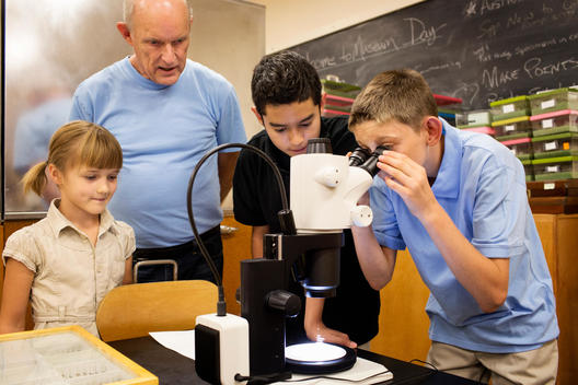 Teacher and students using microscope in laboratory