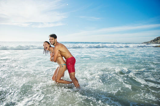 Enthusiastic couple hugging and splashing in ocean