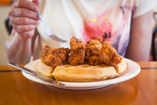 Woman eating a fried chicken and waffle at a restaurant in Satellite Beach, Florida, USA