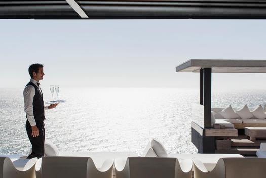 Waiter serving champagne at cabana overlooking ocean