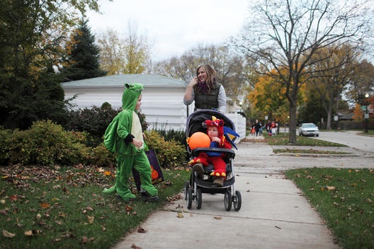 Mother taking her sons dressed as dragons out trick or treating on Halloween