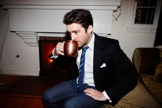 Guy wearing a suit drinking out of mug at a party