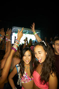 Two women in rave attire making faces at a concert.