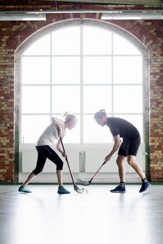 Full length of man and woman playing hockey in health club