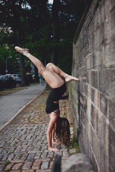 A young female dancer holding a dance pose against a rock wall in Central Park.